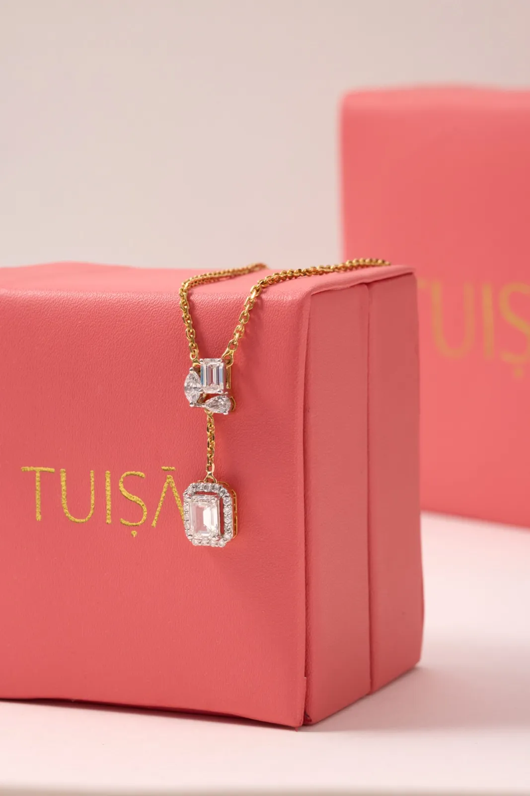 Diamond pendant necklace draped over a coral Tuisa gift box