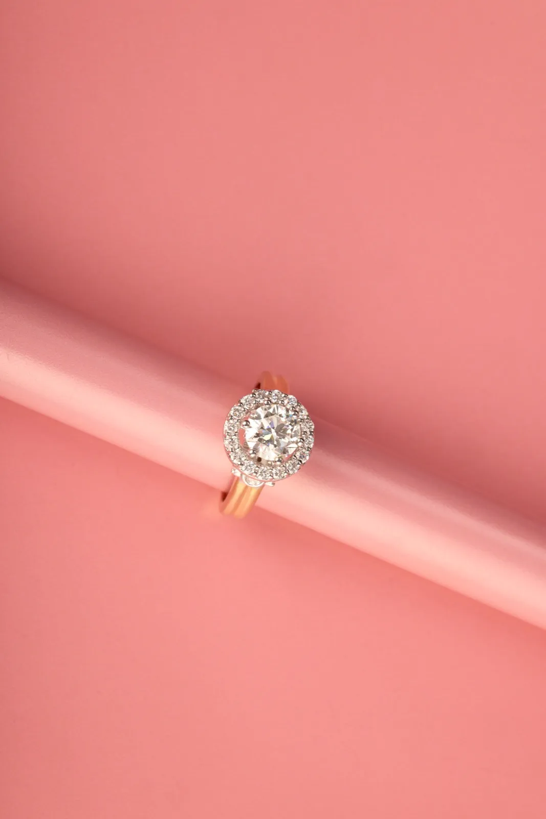 Solitaire diamond ring resting on rolled coral paper